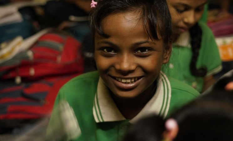 A smiling young girl in a green shirt.